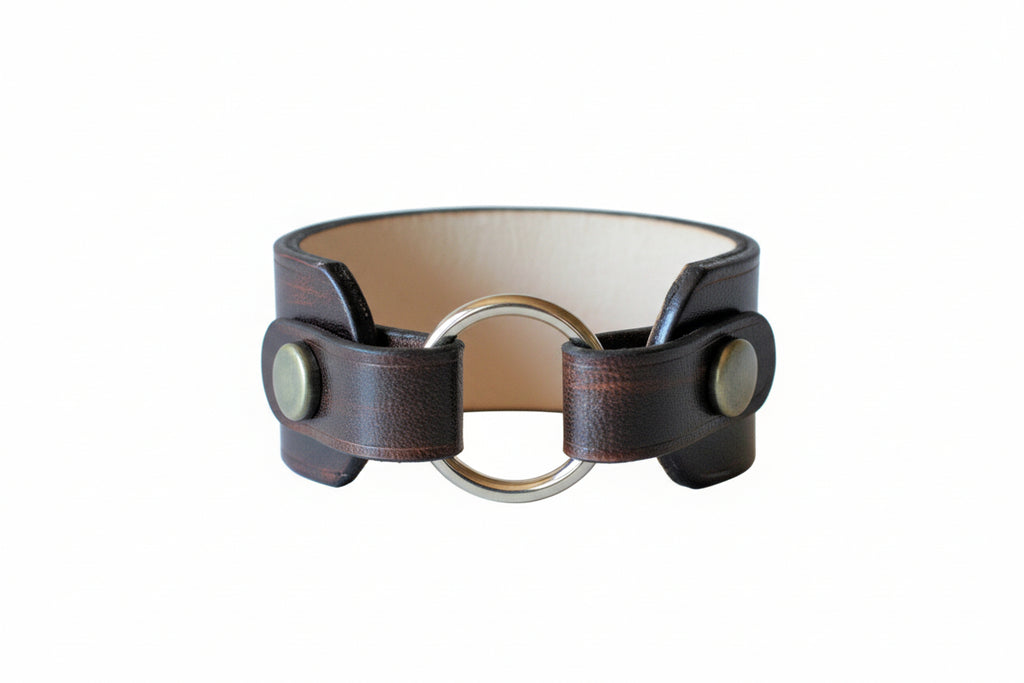 Brown leather bracelet with metal clasp on a wooden surface