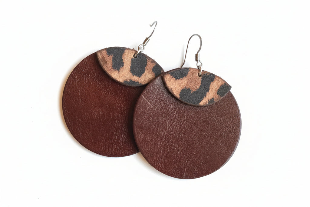 Pair of earrings with brown and leopard print design on a fluffy white surface