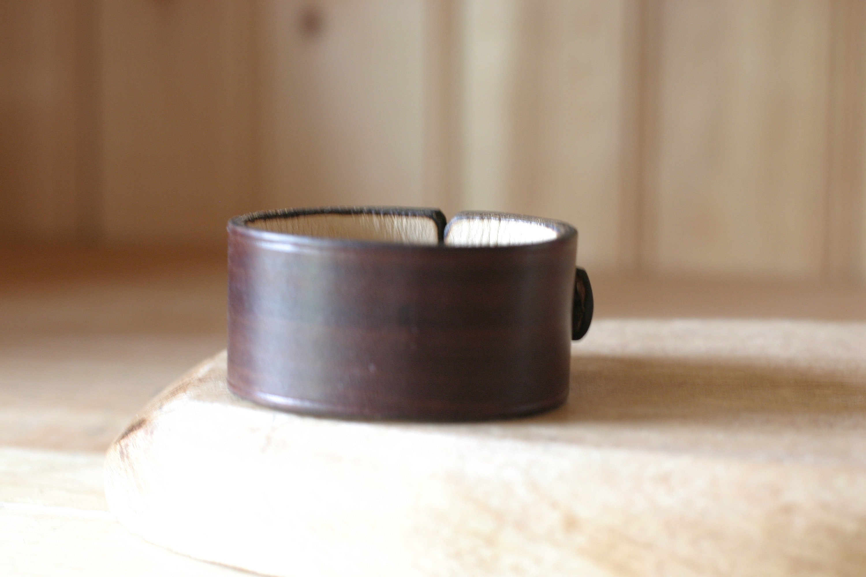 Dark brown leather bracelet on a light wooden surface