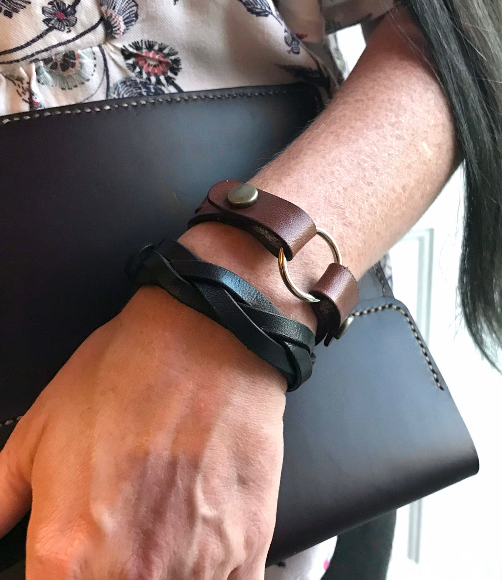 Person wearing a brown leather bracelet on a black background