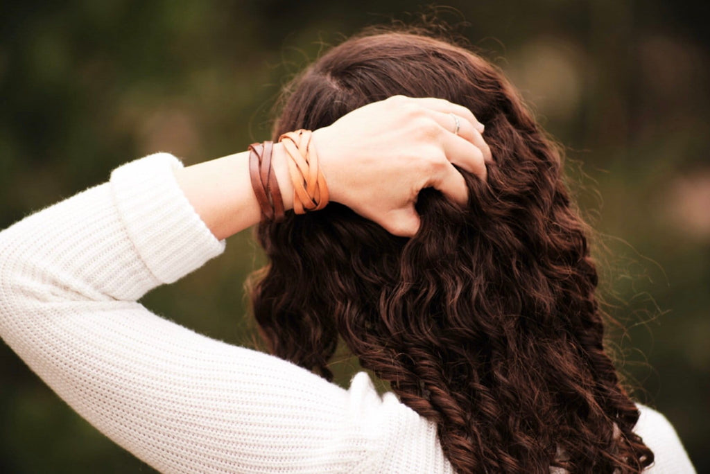 Person with braided hair and a bracelet, with a blurred natural background