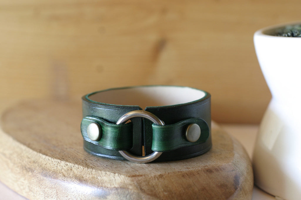 Green leather bracelet with silver clasp on a wooden surface