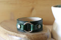 Green leather bracelet with silver clasp on a wooden surface