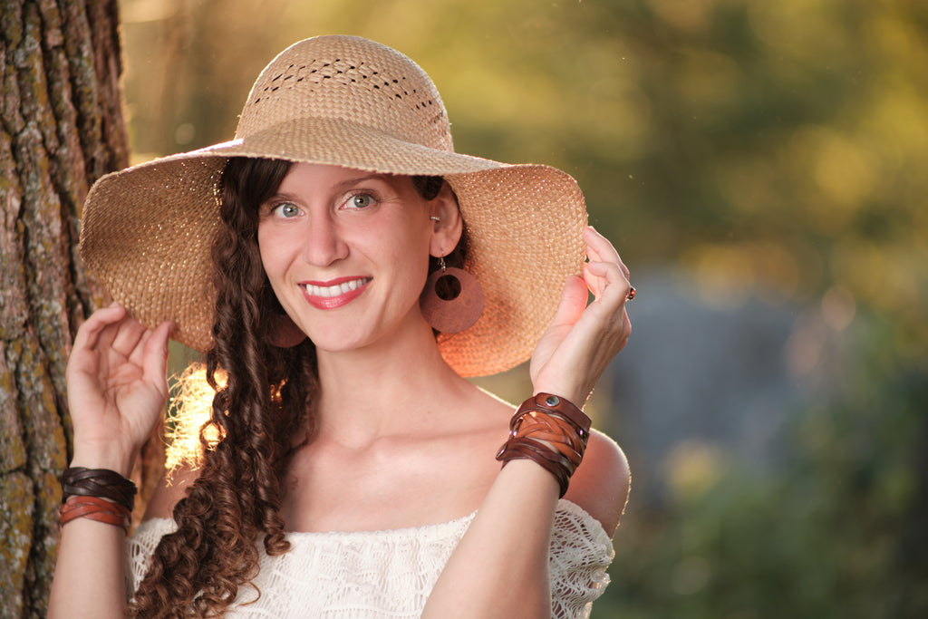 Woman wearing a wide-brimmed straw hat outdoors with a blurred natural background