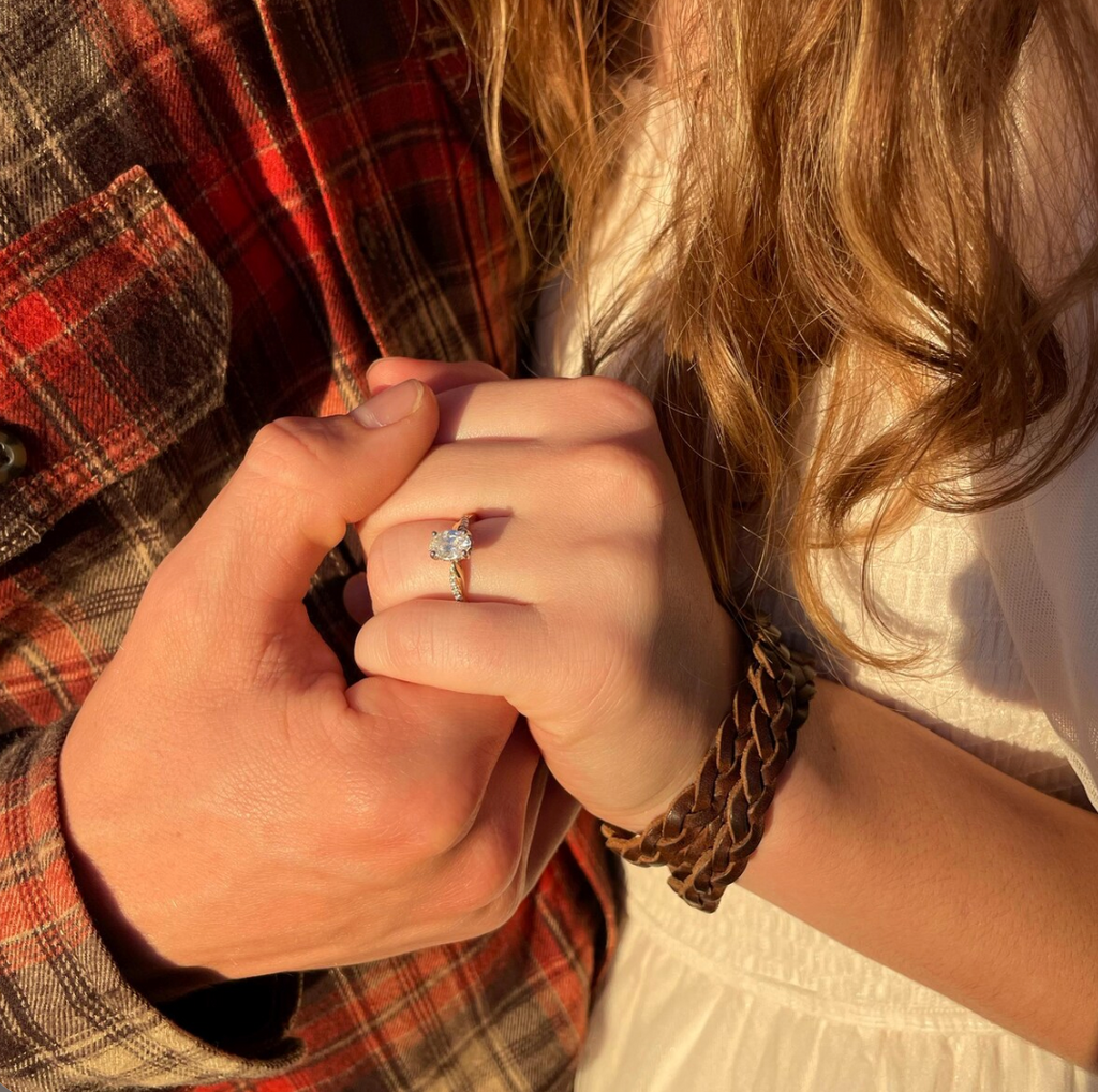 Close-up of a couple holding hands with a focus on an engagement ring.