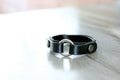 Black leather collar with metal buckle on a light wooden surface