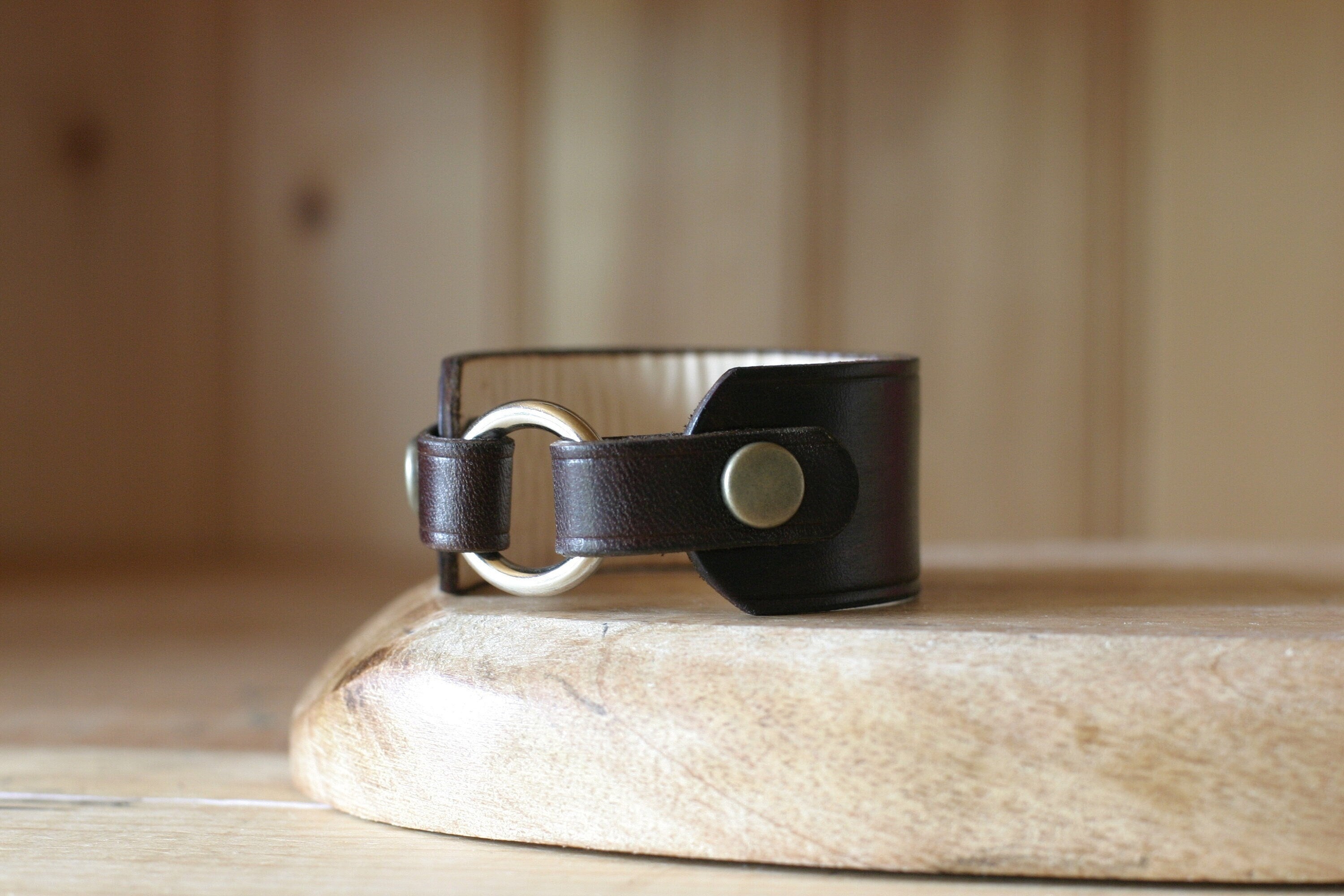 Black leather bracelet with silver clasp on a wooden surface