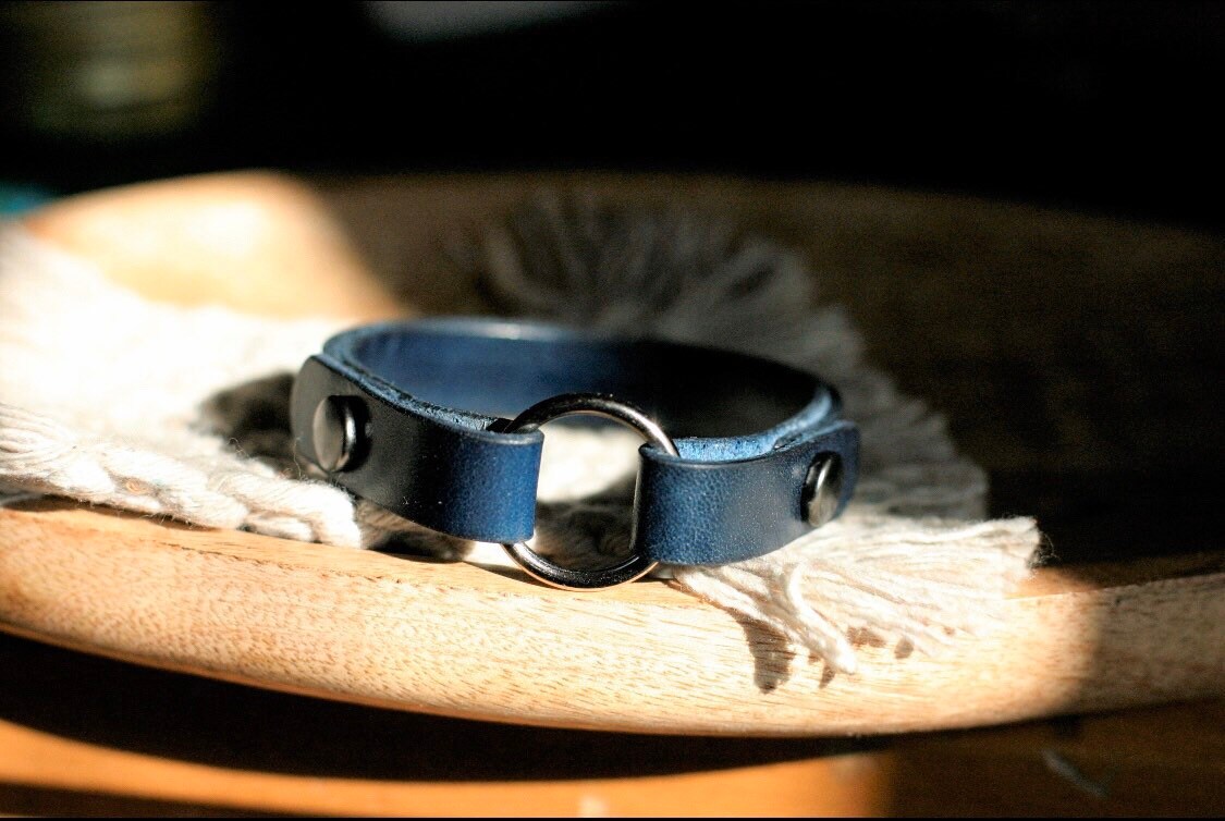 Blue leather wear the ring bracelet with metal buckle on a wooden surface
