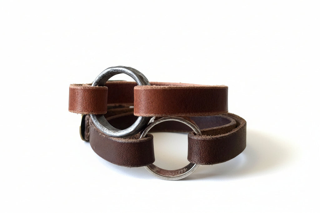 Brown leather bracelets with metal rings on a textured beige background