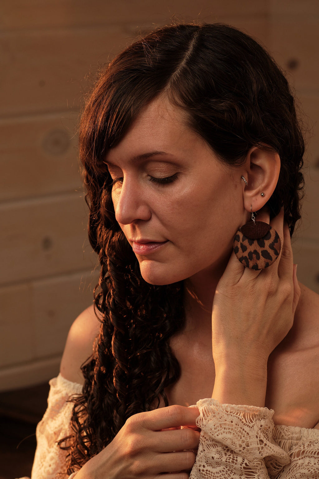 Woman wearing leopard print earrings in a warm-toned setting