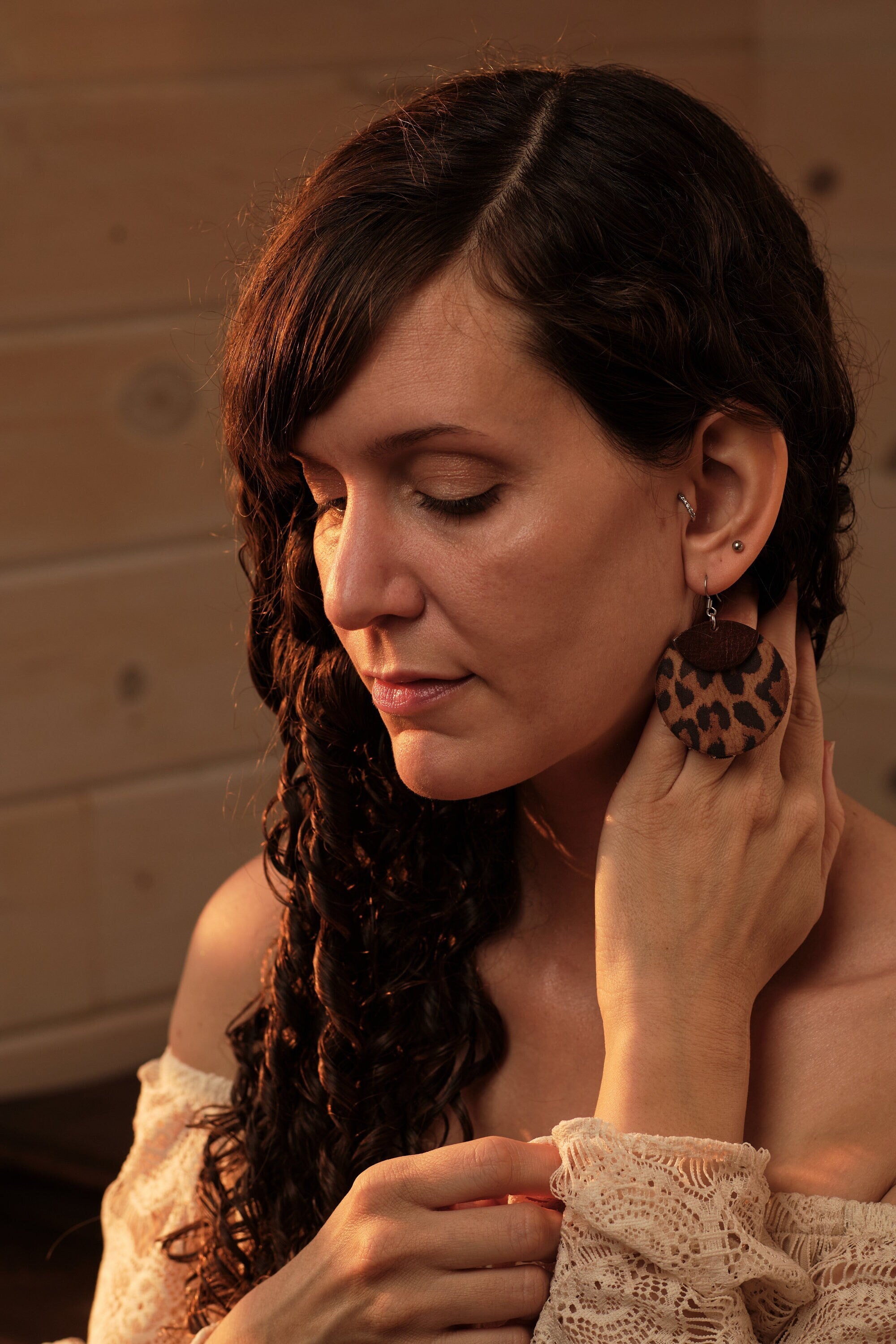 Woman wearing leopard print earrings in a warm-toned setting